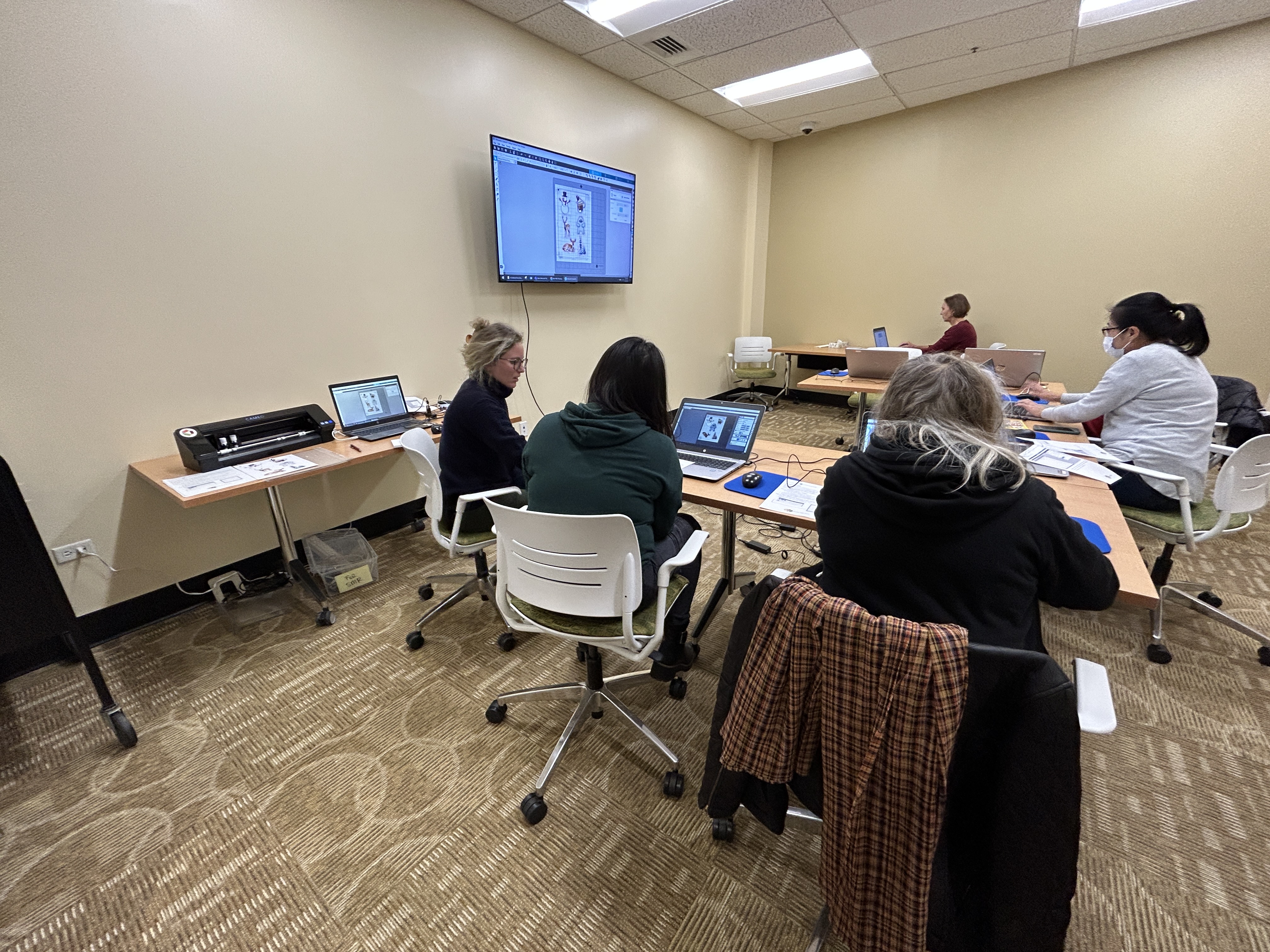 Patrons at a technology program in the library's small meeting room
