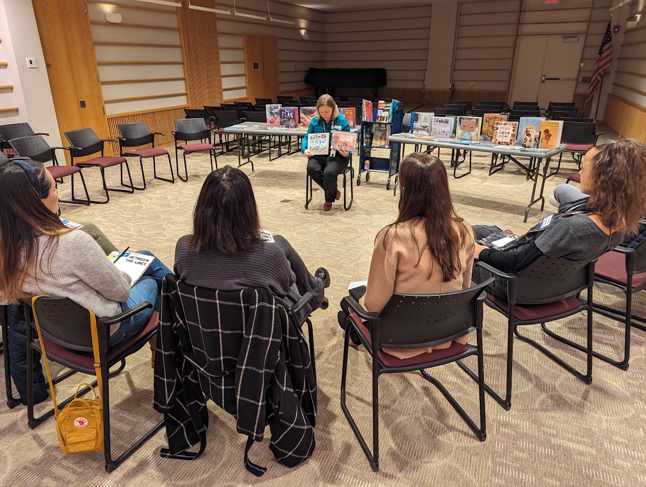 Group of adults watching a librarian show picture books