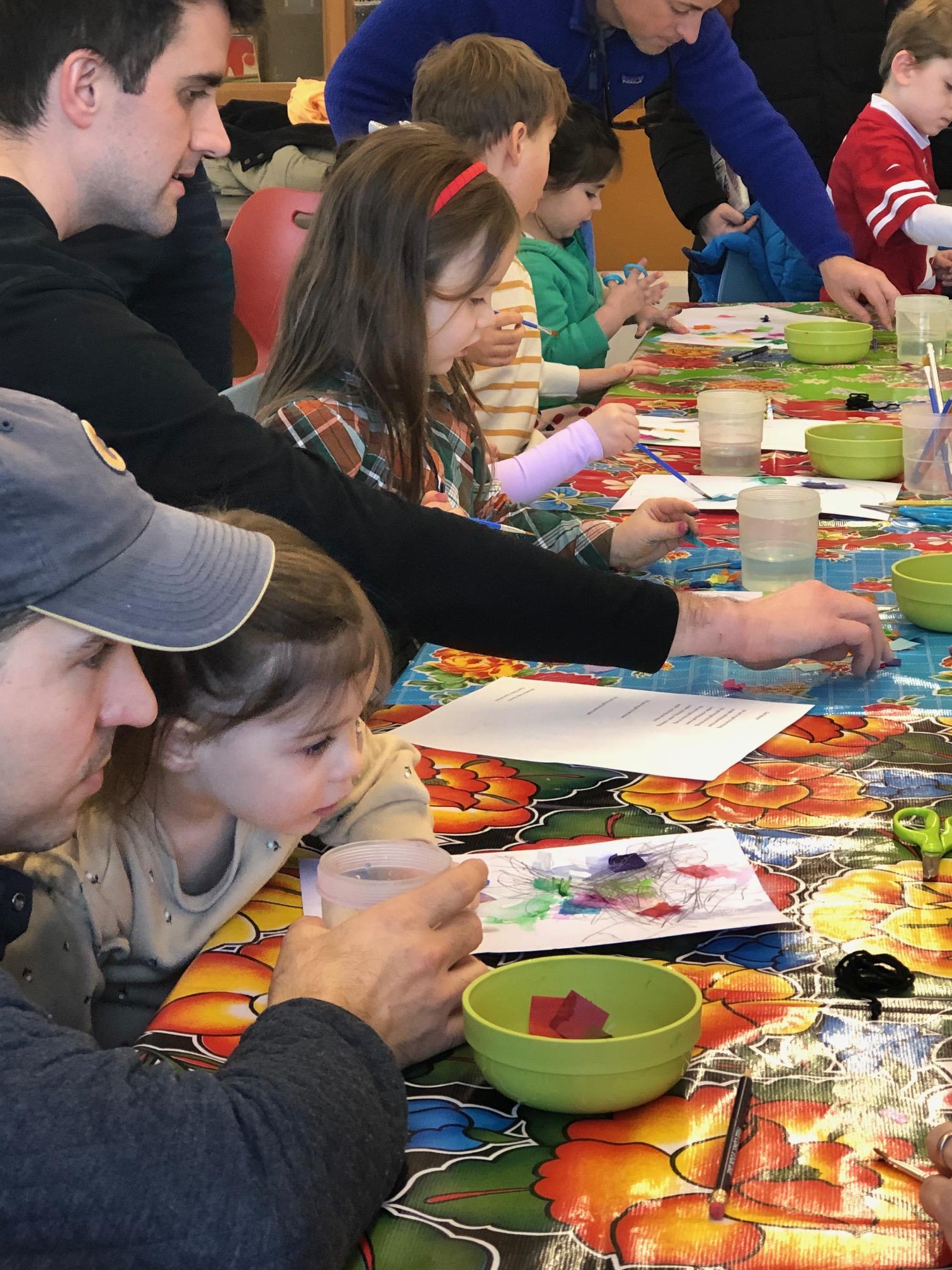 two men and four children make art at a table