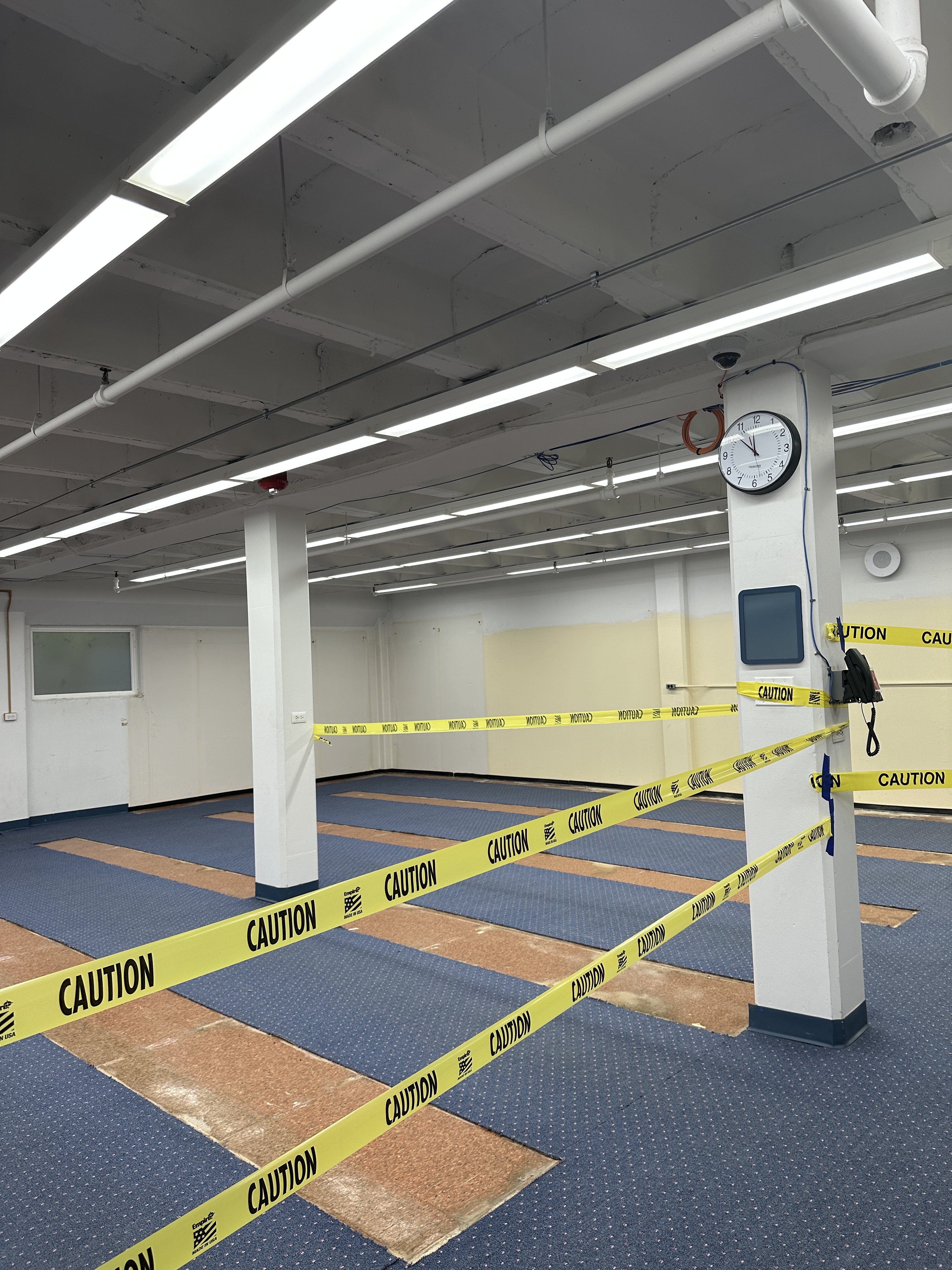 Room with caution tape and damaged carpeting.