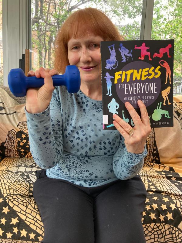Youth Services Librarian Susan holding up "Fitness for Everyone: 50 Exercises for Every Type of Body"