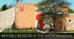 A brick building with a tree in front and text that reads Mitchell Museum of the American Indian