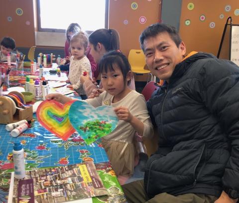 father and daughter painting hearts with children in background